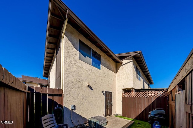 view of property exterior with stucco siding, a patio, and a fenced backyard