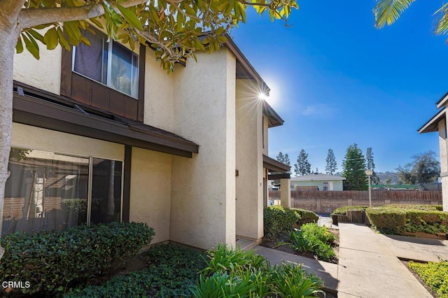 view of side of property with stucco siding and fence