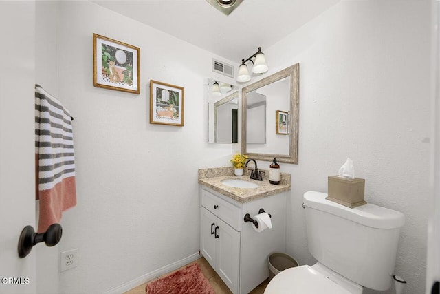 bathroom featuring baseboards, visible vents, toilet, and vanity