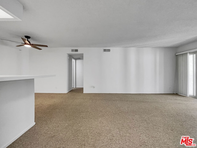 carpeted spare room featuring a textured ceiling and ceiling fan