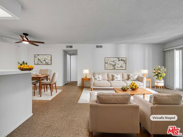 carpeted living room with a textured ceiling and ceiling fan