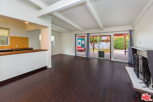 unfurnished living room with a fireplace, beam ceiling, hardwood / wood-style flooring, and sink