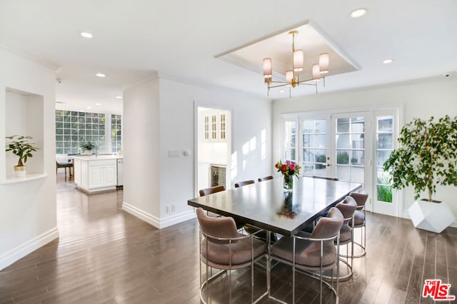 dining area featuring french doors, a raised ceiling, a chandelier, and dark wood-type flooring