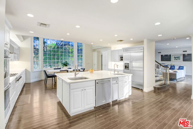 kitchen featuring appliances with stainless steel finishes, white cabinetry, a kitchen island with sink, and sink