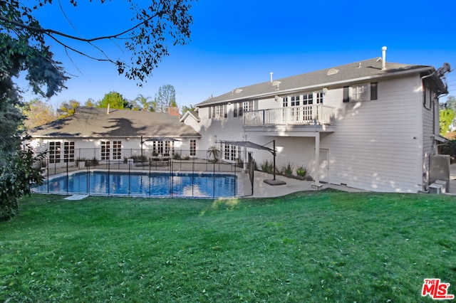 rear view of property with a balcony, a patio, and a yard