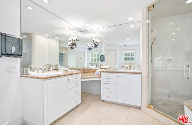 bathroom with a shower with door, vanity, and tile patterned floors