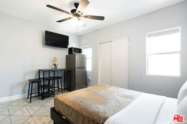 tiled bedroom featuring ceiling fan and stainless steel refrigerator