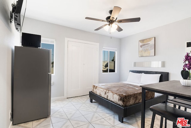 bedroom with ceiling fan, stainless steel fridge, and a closet