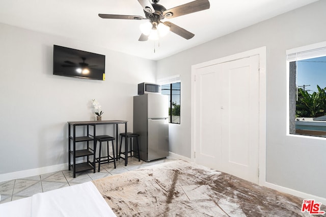 tiled bedroom with stainless steel refrigerator, ceiling fan, and a closet