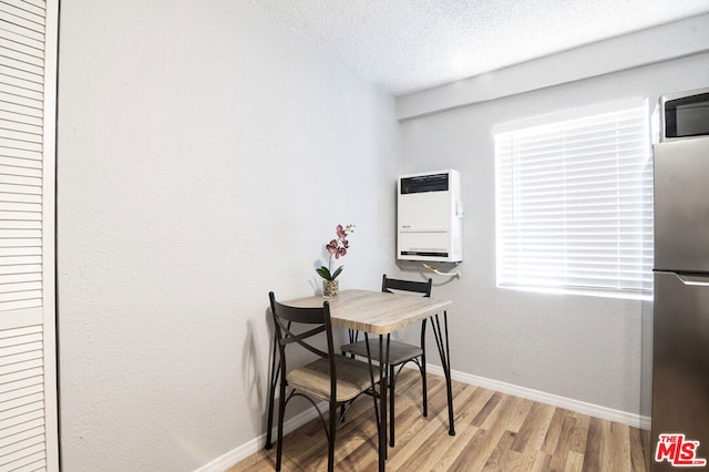 dining space with a textured ceiling, light wood-type flooring, and heating unit