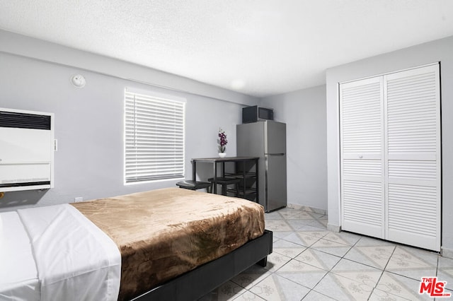 bedroom with heating unit, stainless steel refrigerator, and a closet