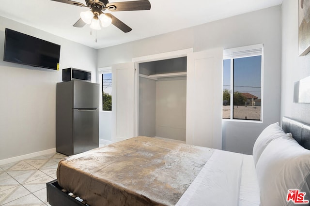 bedroom with stainless steel fridge, a closet, ceiling fan, and light tile patterned flooring