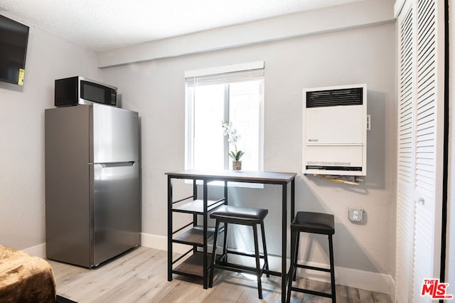 kitchen featuring light hardwood / wood-style floors, a textured ceiling, stainless steel refrigerator, and heating unit