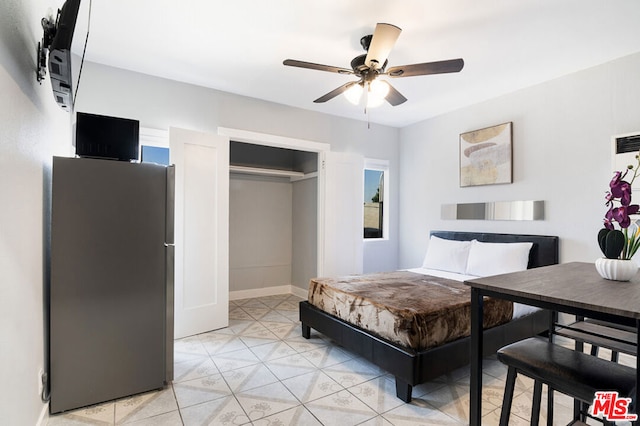 bedroom with stainless steel refrigerator, ceiling fan, and a closet