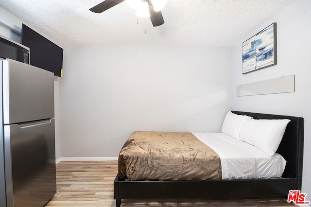 bedroom with stainless steel refrigerator, ceiling fan, a textured ceiling, and light wood-type flooring