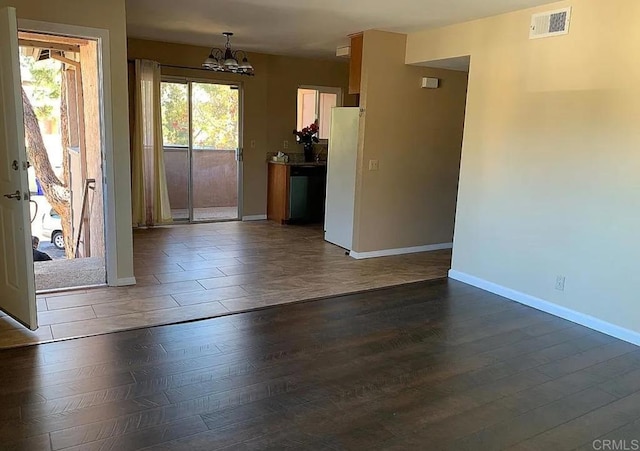 empty room with a chandelier and dark hardwood / wood-style floors