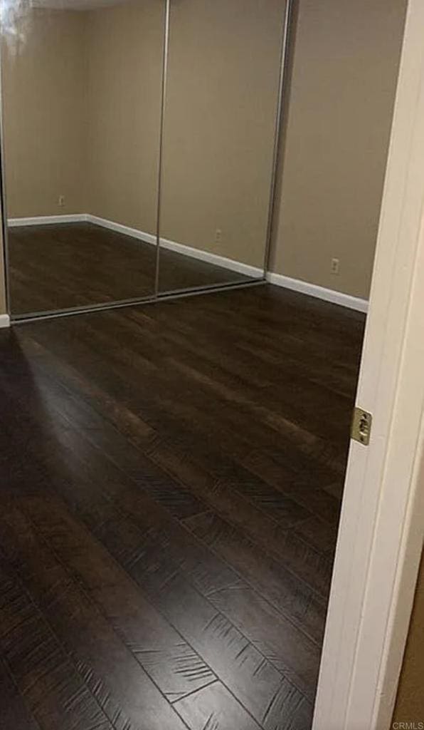 unfurnished bedroom with dark wood-type flooring