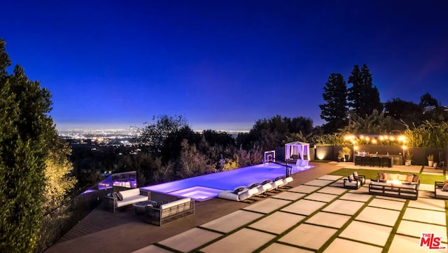 pool at dusk with a patio area, an outdoor living space with a fire pit, and an in ground hot tub