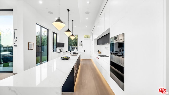 kitchen with pendant lighting, light hardwood / wood-style flooring, white cabinets, and a large island