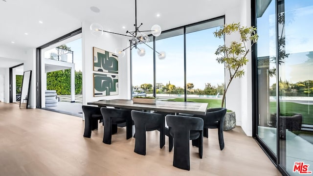 dining room featuring a healthy amount of sunlight, a notable chandelier, floor to ceiling windows, and light hardwood / wood-style floors