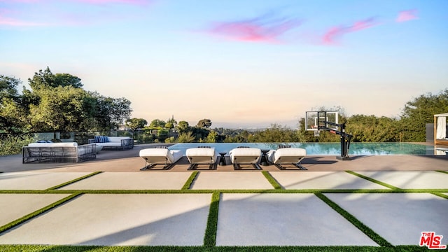 patio terrace at dusk with outdoor lounge area and basketball hoop