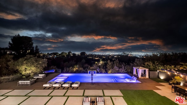 pool at dusk featuring a storage shed and a patio