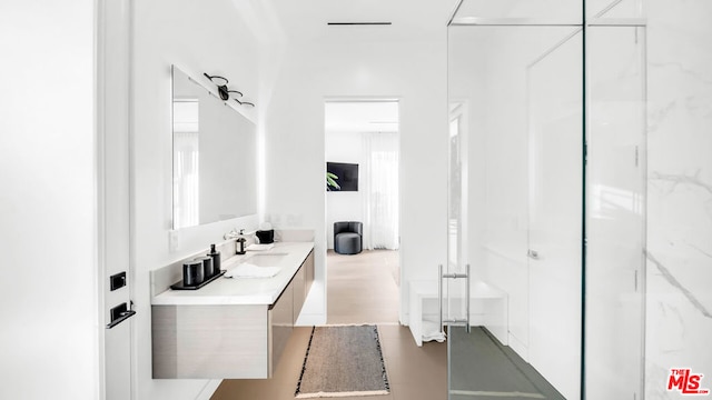 bathroom featuring a shower with door and vanity