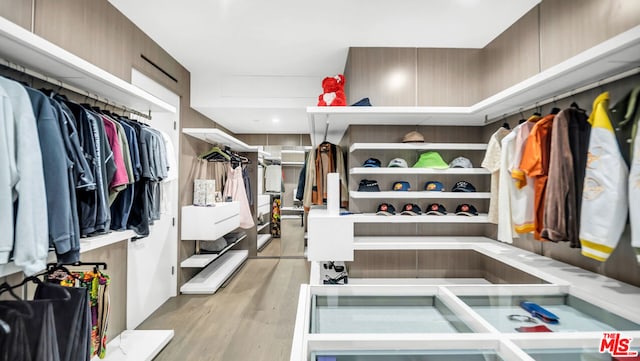 walk in closet with light hardwood / wood-style flooring