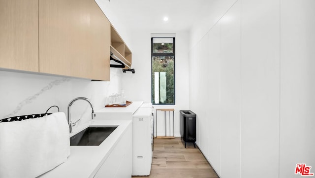 kitchen with light wood-type flooring, white cabinetry, light brown cabinetry, and sink