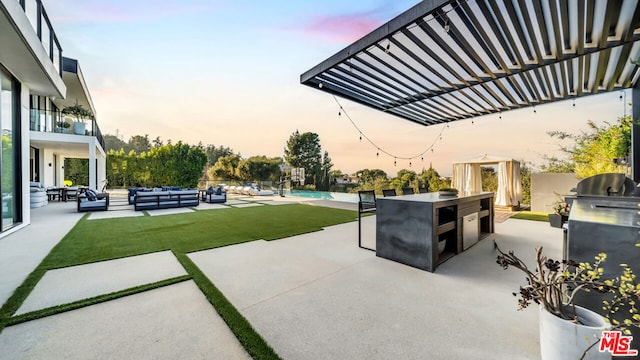 patio terrace at dusk with an outdoor living space, an outdoor kitchen, and a bar