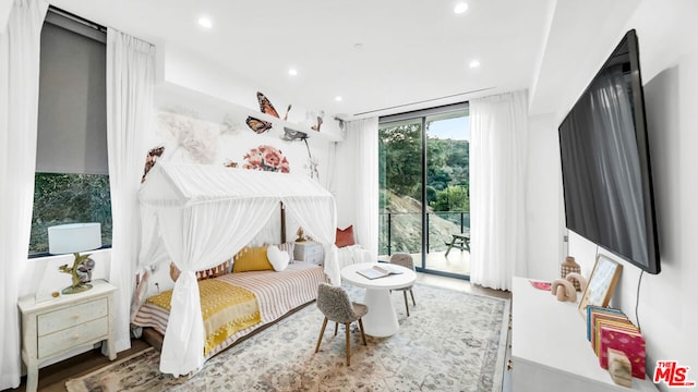 bedroom with access to exterior, a wall of windows, and hardwood / wood-style floors