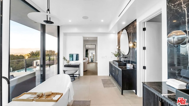 bathroom with a tub to relax in, vanity, and tile patterned floors