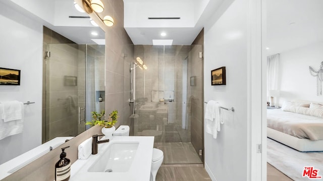 bathroom featuring toilet, a shower with shower door, and sink