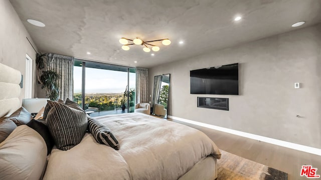 bedroom featuring a wall of windows, access to exterior, and hardwood / wood-style flooring