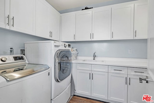 laundry room featuring washing machine and dryer, sink, cabinets, and dark hardwood / wood-style flooring