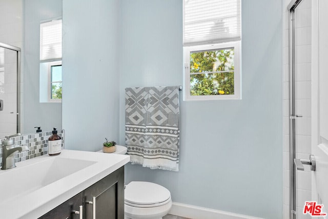 bathroom featuring vanity, toilet, and a shower with shower door