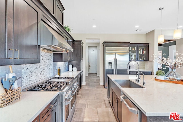 kitchen featuring decorative backsplash, light stone countertops, sink, high quality appliances, and hanging light fixtures