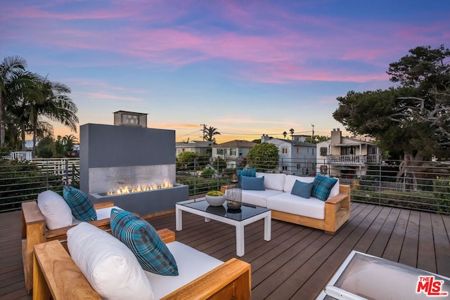 deck at dusk featuring an outdoor living space with a fire pit