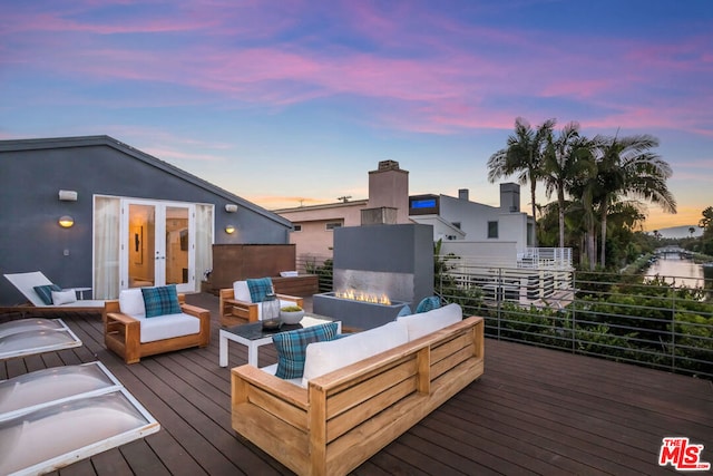 deck at dusk featuring an outdoor living space with a fire pit