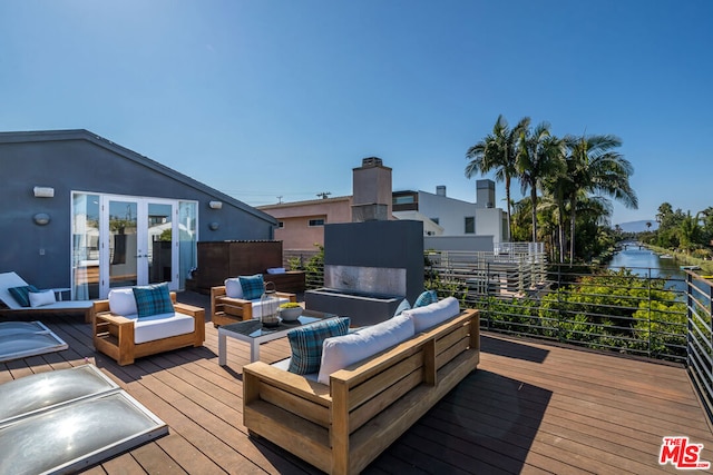 deck with a water view, an outdoor hangout area, and french doors