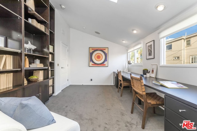 carpeted home office featuring built in desk and lofted ceiling