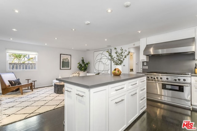 kitchen featuring white cabinets, wall chimney exhaust hood, dark wood-type flooring, and range with two ovens