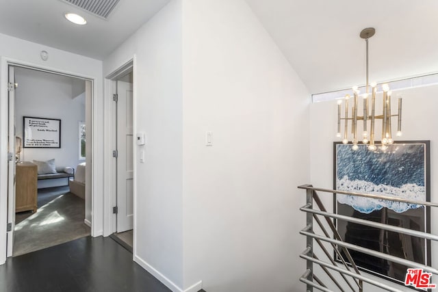 hallway featuring a chandelier and dark wood-type flooring