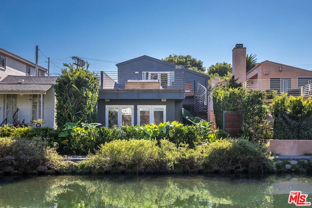 rear view of house with a water view and a balcony