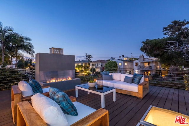 deck at dusk with an outdoor living space with a fire pit