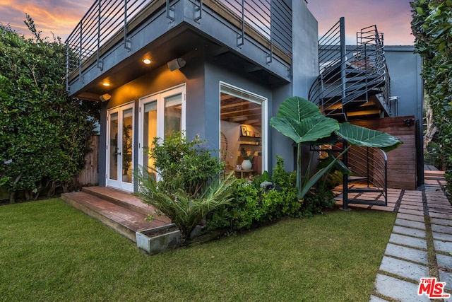 property exterior at dusk featuring a lawn