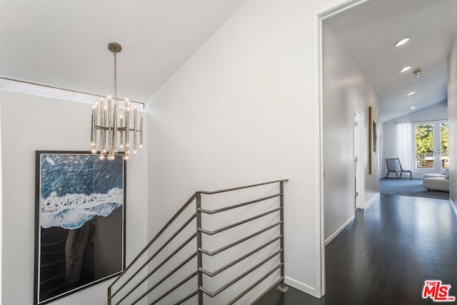 hallway with a notable chandelier, dark hardwood / wood-style floors, and vaulted ceiling