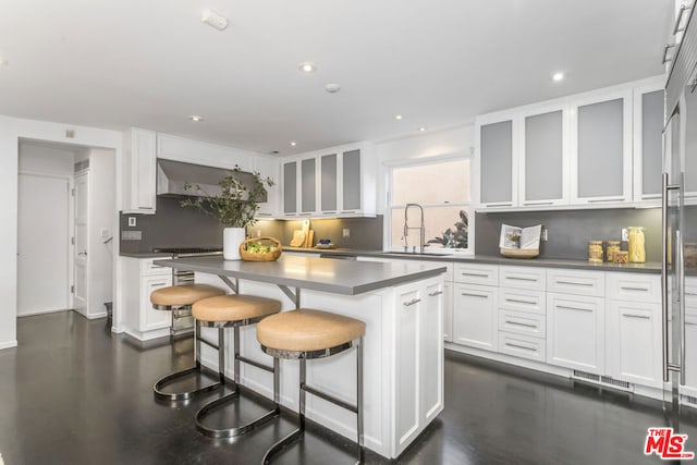 kitchen featuring white cabinets, decorative backsplash, sink, and a kitchen island