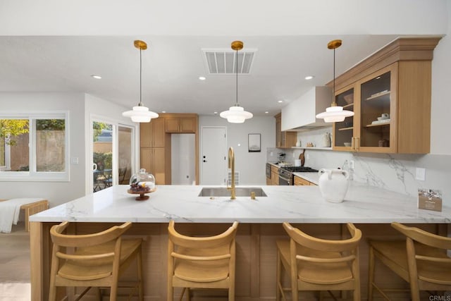 kitchen with sink, hanging light fixtures, light stone countertops, tasteful backsplash, and kitchen peninsula