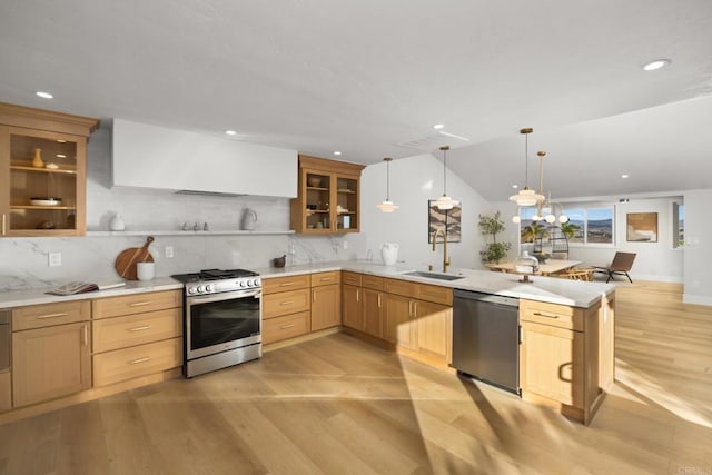 kitchen with sink, wall chimney exhaust hood, decorative light fixtures, kitchen peninsula, and stainless steel appliances